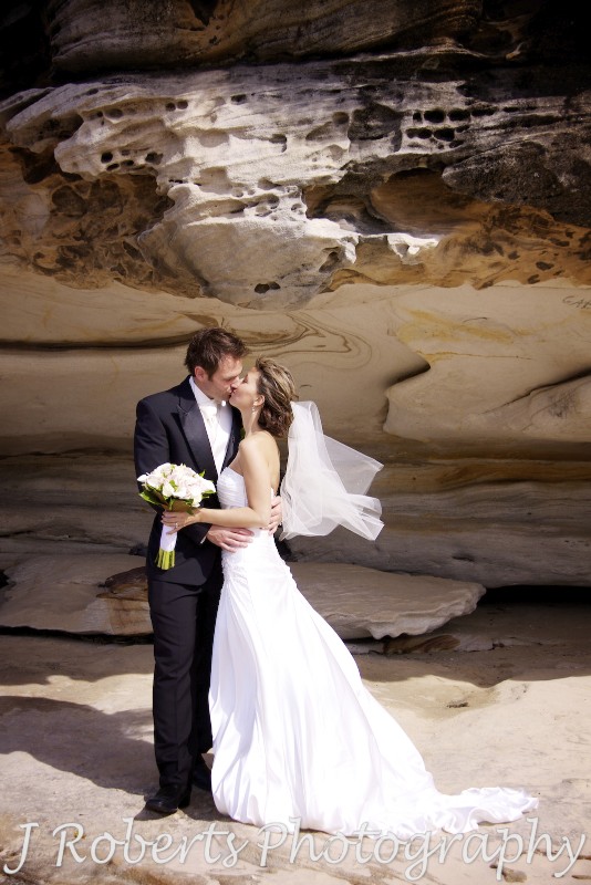 Bride and groom in front of a sandstone rock wall at Balmoral beach - wedding photography sydney